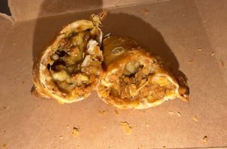 Two halves of a sliced savory pastry or stuffed bread roll with herbs and filling visible on a tan surface